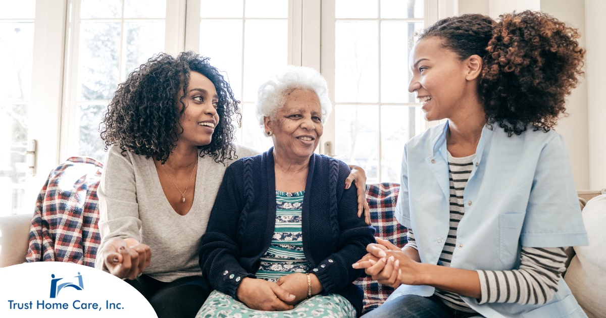 A caregiver talks with a client and her daughter, representing the type of communication that is vital when taking on a person-centered care approach.