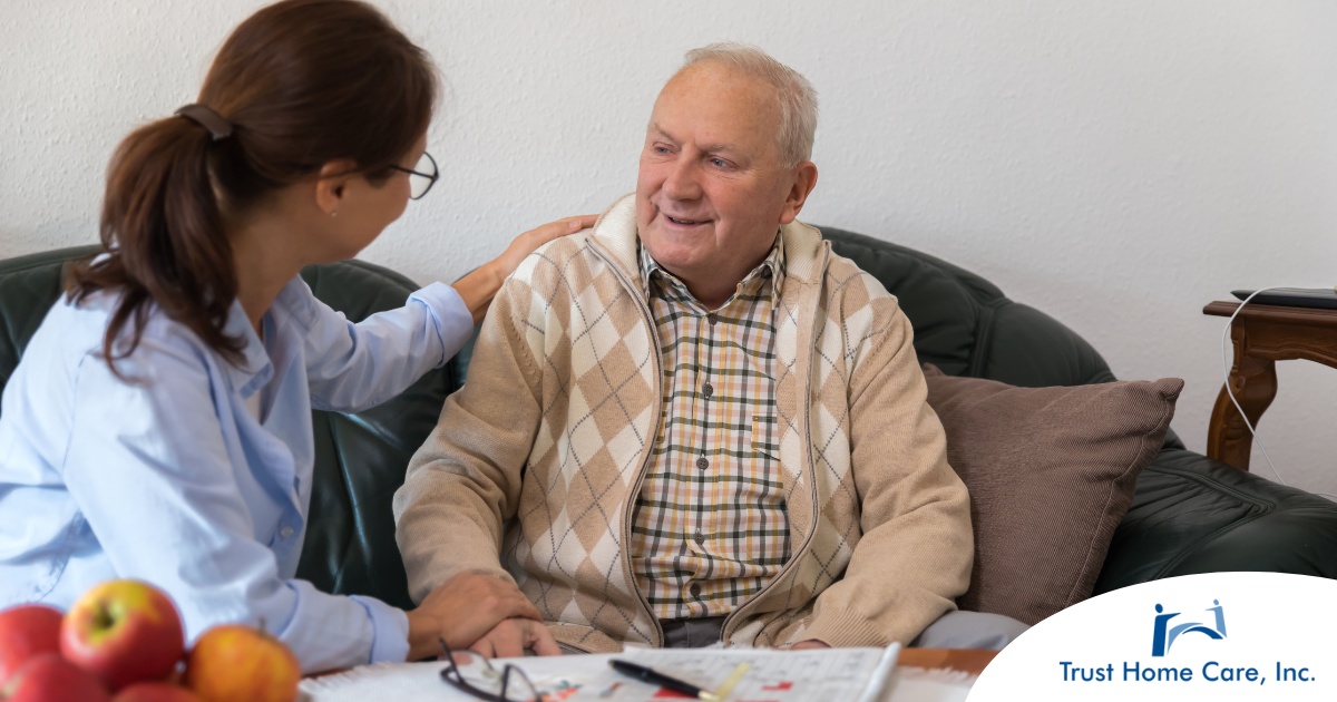 A caregiver compassionately listens to an older man, representing the kind of patience and empathy that help with communicating with clients who have dementia.