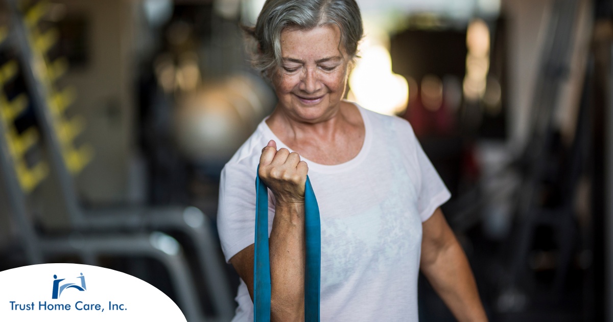 An older woman uses a resistance band to exercise, representing how staying active can help older adults keep their blood pressure in a healthy range.