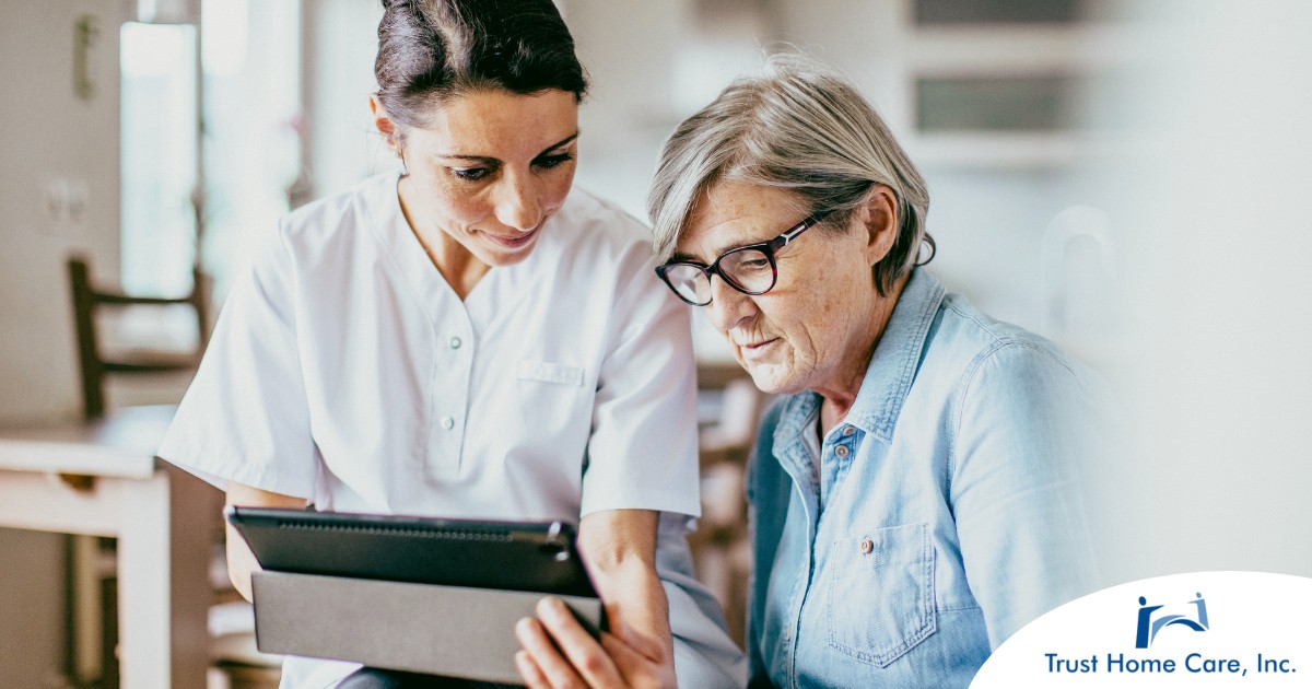 Innovations-in-Home-Health-Care-The-Evolving-Role-of-Registered-Nurses A nurse helps an older patient by showing her a tablet representing the role of tech in registered nurses’ roles in care.