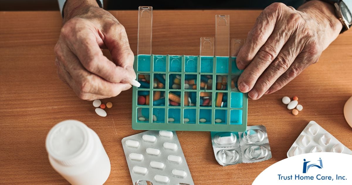 The-Caregivers-Guide-to-Managing-Medications-for-Older-Adults Older hands organize pills into a pill organizer, showing a great tool for managing medications.