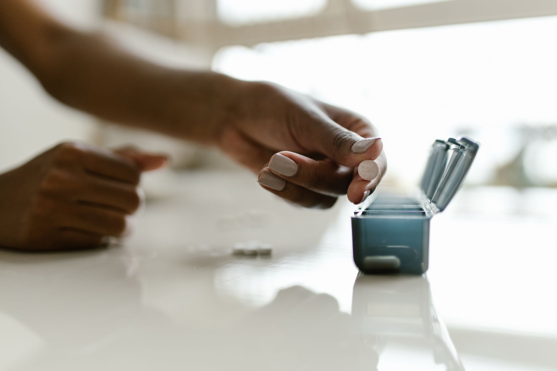 A caregiver organizing pills into a weekly organizer during medication management in Sterling, VA